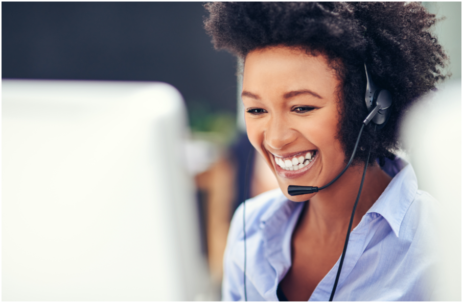 Image of a very happy woman at a computer with a headset on
