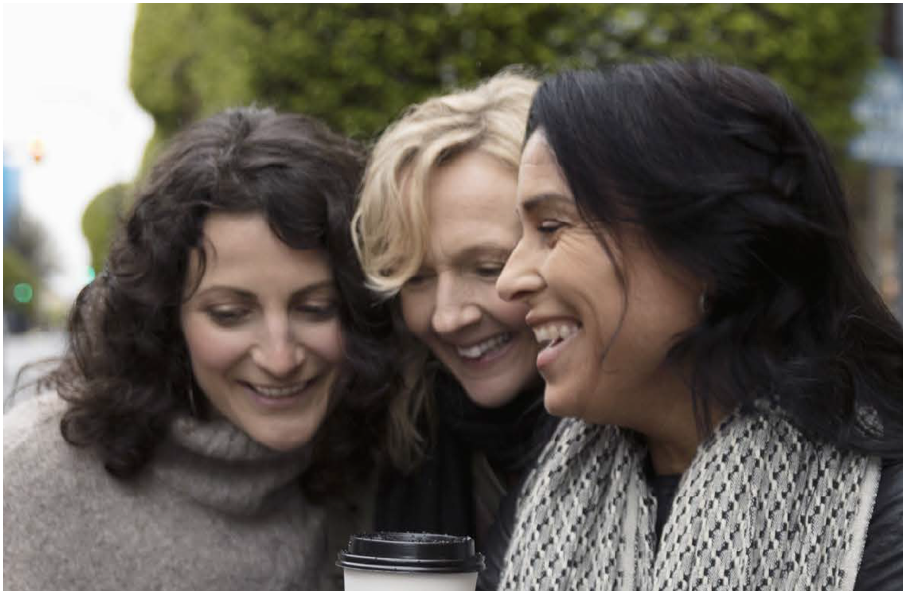 Image of three happy women looking down at something