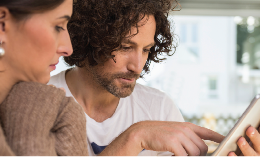 Image of man and a woman looking and pointing at a tablet device